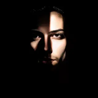 A portrait with dramatic split lighting — half the face brig