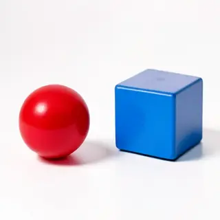A red ball and a blue cube sitting side by side on a white s