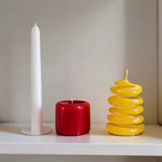 A tall thin white candle, a short fat red candle, and a medi