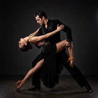 Two tango dancers in a close embrace, the man dipping the wo