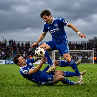 Two soccer players mid-tackle, one sliding and the other jum