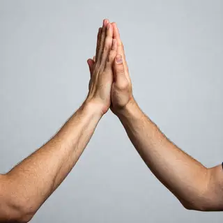 Two people doing a high-five, palms meeting with all fingers