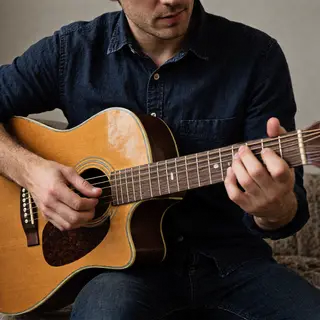 A person playing an acoustic guitar with left hand on the fr