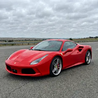 A bright red sports car parked on a gray asphalt road — the 