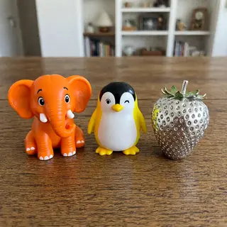 An orange elephant, a yellow penguin, and a silver strawberr