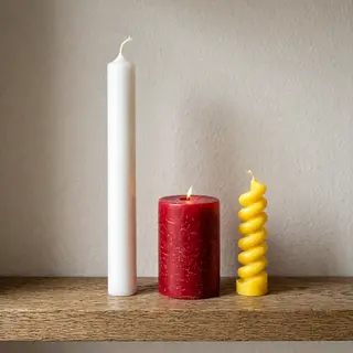 A tall thin white candle, a short fat red candle, and a medi