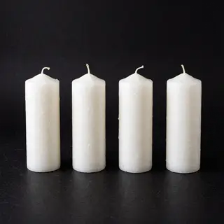 Exactly 4 white candles standing on a dark surface