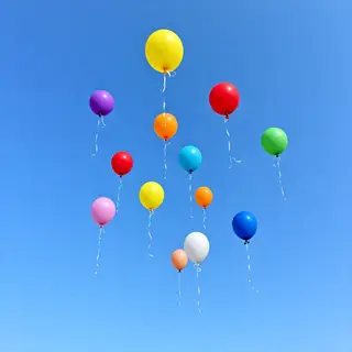 Exactly 11 colorful balloons floating against a clear blue s