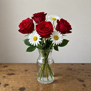 4 red roses and 2 white daisies in a glass vase on a table