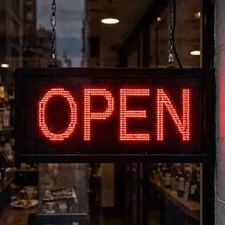 The word 'OPEN' displayed on a red LED sign with glowing pix