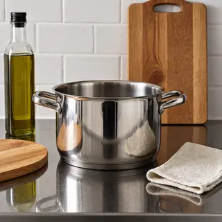 A kitchen counter with a stainless steel pot, a wooden cutti