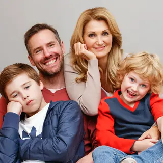 A family photo with four people: a father beaming with pride