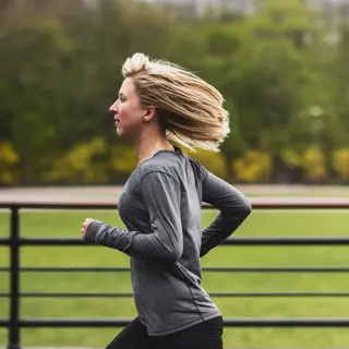 A woman mid-stride running through a park, hair and clothes 