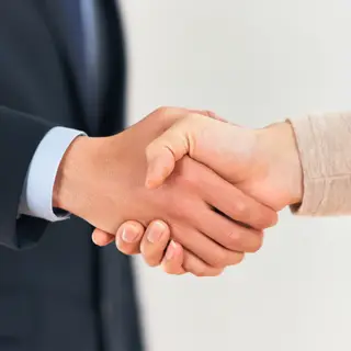 Two people shaking hands in a professional setting, all fing