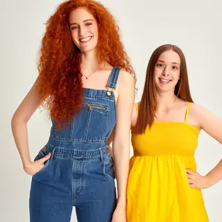 Two friends posing: one tall with curly red hair in denim ov