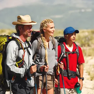 Three hikers on a trail: a man with a backpack and sunhat, a