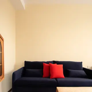 A minimalist room with walls in #F5E6CC (warm cream), a sofa