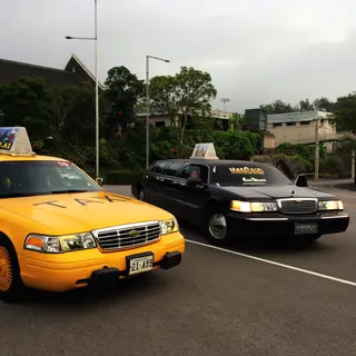 A yellow taxi and a black limousine parked next to each othe
