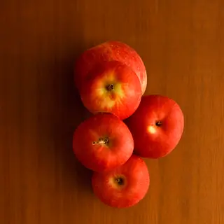 Exactly 3 red apples arranged on a wooden table