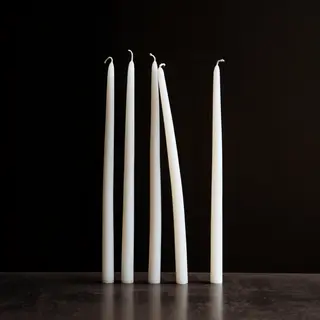 Exactly 4 white candles standing on a dark surface