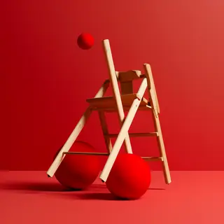A red ball underneath a wooden chair