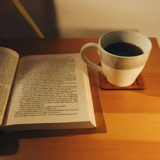 A coffee mug next to an open book on a desk