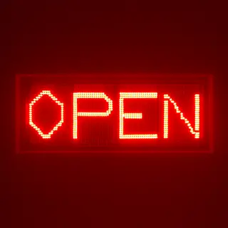 The word 'OPEN' displayed on a red LED sign with glowing pix