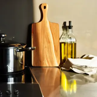 A kitchen counter with a stainless steel pot, a wooden cutti