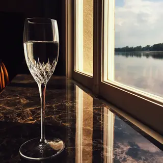 A crystal wine glass on a polished marble counter next to a 
