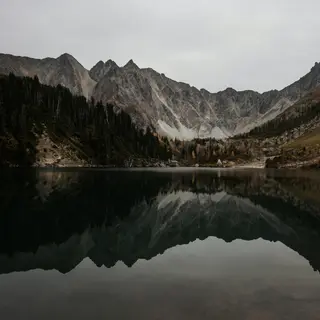 A mountain range reflected in a still alpine lake, with the 
