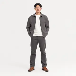 A man standing straight facing the camera, hands in pockets,