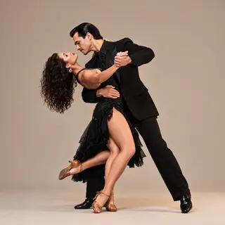 Two tango dancers in a close embrace, the man dipping the wo