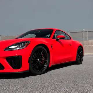 A bright red sports car parked on a gray asphalt road — the 