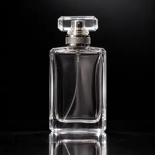 A clear glass perfume bottle on a reflective black surface w