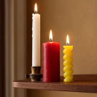 A tall thin white candle, a short fat red candle, and a medi
