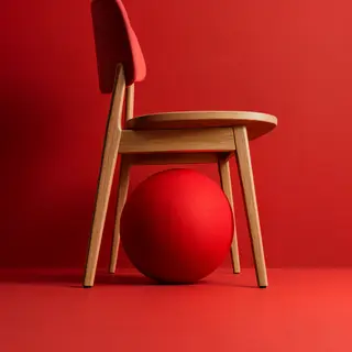 A red ball underneath a wooden chair