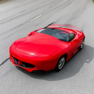 A bright red sports car parked on a gray asphalt road — the 