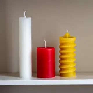 A tall thin white candle, a short fat red candle, and a medi
