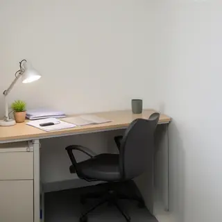 An office workspace with a desk, chair, bookshelf, and lamp 