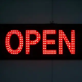 The word 'OPEN' displayed on a red LED sign with glowing pix