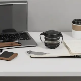 A workspace desk with a brushed aluminum laptop, a leather-b