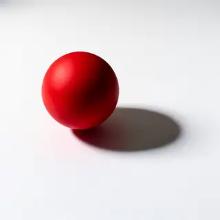A red sphere on a white surface with a single shadow cast to