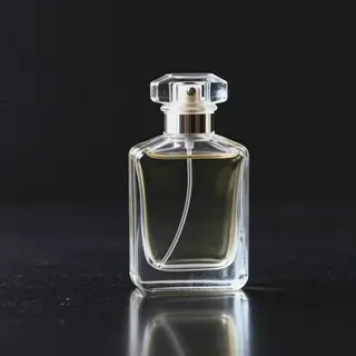 A clear glass perfume bottle on a reflective black surface w