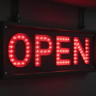 The word 'OPEN' displayed on a red LED sign with glowing pix