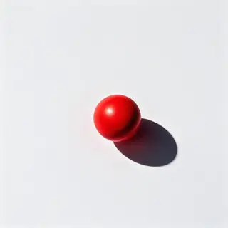 A red sphere on a white surface with a single shadow cast to