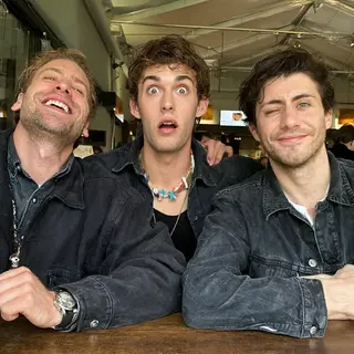 A group of three friends at a table: one laughing with head 