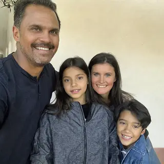 A family photo with four people: a father beaming with pride