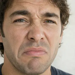 A close-up of a person's face showing clear disgust, nose wr