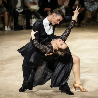 Two tango dancers in a close embrace, the man dipping the wo