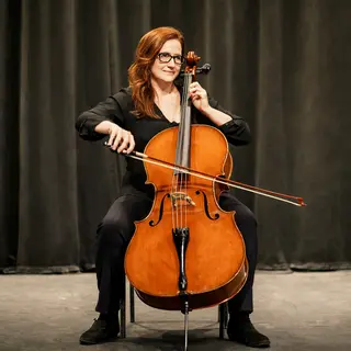 A cellist seated with correct posture, legs around the instr